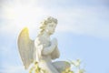 Ancient statue of little guards angel in flowers and  in the sunlight. Love, faith, hope, religion, Christianity, good concept Royalty Free Stock Photo