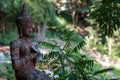 An ancient statue of a meditating buddha against a backdrop of a green forest or jungle. Royalty Free Stock Photo