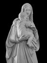 Ancient statue of the mother Vigin Mary carrying the baby Jesus Isolated on black background with clipping path