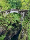 Ancient stone arch bridge over a deep gorge surrounded by lush foliage at Orrido di Sant\'Anna, Traffiume, Cannobio, Piemont Royalty Free Stock Photo