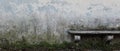 Ancient stone bench in front of old gray wall with crumbling plaster and green moss. Narrow vintage background