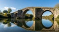 Ancient Stone Bridge Arches Reflected in Calm River Water Royalty Free Stock Photo