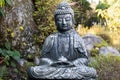 A stone figure of a Buddha sitting with a bowl and meditating