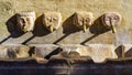 Ancient stone fountain with human faces and jets of water supplying fresh water, Andalucia, Spain.