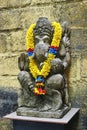 Ancient stone Ganesha statue with floral garland in Bali