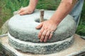 The ancient stone hand grain mill. Men`s hands rotate a stone millstone Royalty Free Stock Photo