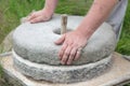 The ancient stone hand grain mill. Men`s hands rotate a stone millstone Royalty Free Stock Photo