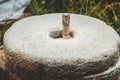 The ancient stone hand mill with grain. Medieval hand-driven millstone grinding wheat. Old quern stone hand mill with