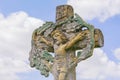 Ancient stone sculpture of Jesus Christ, crucified on a cross. Sky background Royalty Free Stock Photo