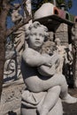 Ancient stone sculpture of naked cherub playing lute in reclamation yard