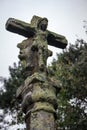 Ancient stone statue with ruined jesus christ figure. Medieval religious sculpture. Old cross with moss and jesus figure.