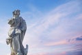 Ancient stone statue of St. John the Evangelist with eagle against blue sky