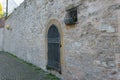 An ancient stone wall with a door and a small window, closed with wrought iron bars Royalty Free Stock Photo