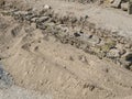 Ancient stone wall under reconstruction with rocks methodically stacked in sandy soil Royalty Free Stock Photo
