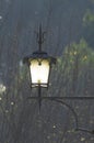 Ancient street lamp lit at dusk Royalty Free Stock Photo