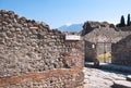 Ancient street and ruined houses in the ancient town of Pompeii, Italy. The peak of Mount Vesuvius can be seen in the background Royalty Free Stock Photo