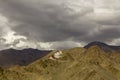 A ancient Tibetan monastery on a sandy desert mountain under a rainy sky