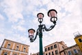 An ancient triple metal street lamp, with pink plafonds against the sky and buildings of Venice, Italy. Vintage street