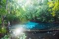 Ancient turquoise pond in tropical forest. Sunbeam shines through the branches of trees on the pond and lush foliage. Tourist Royalty Free Stock Photo