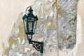 Ancient twisted lantern, the lamp is on the wall with peeling plaster in Prague Royalty Free Stock Photo