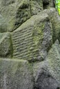 Ancient, weathered carved stone blocks. Decorative masonry overgrown, green moss