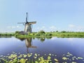 Ancient wind mill reflected in a blue canal on a summer day Royalty Free Stock Photo