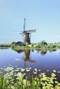 Ancient wind mill reflected in a blue canal on a summer day Royalty Free Stock Photo