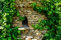 An ancient window in a house made of stones, covered with ivy. Fairytale house. Royalty Free Stock Photo