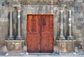 Ancient wooden double doors in an old stone building with pillars