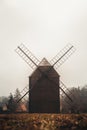 Ancient wooden mill standing alone in a field in gloomy foggy weather. Historical building for grinding corn, Opava, Czech