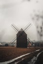 Ancient wooden mill standing alone in a field in gloomy foggy weather. Historical building for grinding corn, Opava, Czech