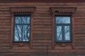 Ancient wooden wall of old house with windows in carved frame. Royalty Free Stock Photo