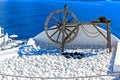 Ancient wooden wheel and white painted pebbles in Santorini, Greek Islands