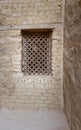 Ancient wooden window with geometrical pattern based on the christian cross on external brick stone wall