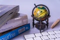An ancient world globe, books, pen and keyboard Royalty Free Stock Photo