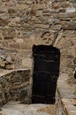 Ancient wrought iron door in the wall of an old, ancient fortress. Maltese cross carved in stone. Royalty Free Stock Photo