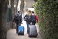 Tourists travelers carrying suitcases in hand walking