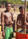 Andranovory, Madagascar - April 30, 2019: Two unknown Malagasy men extracting juice from fruits in large barrel with wooden pole