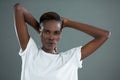 Androgynous man posing with hands behind head against grey background Royalty Free Stock Photo