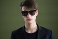 Androgynous man in sunglasses posing against green background Royalty Free Stock Photo