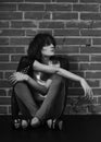 Androgyny female model in Heroin chic style near brick wall.