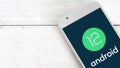 Android 12 logo on a screen of a mobile on a white wooden table. Royalty Free Stock Photo