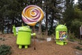 Android lollipop and jelly bean statues in front of tall trees at garden