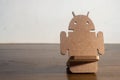 Android made of MDF wood, placed on a wooden table with copy space left,future concept, mobile operating system
