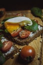 andwich with cream cheese, cherry tomatoes, poached egg, spinach and spices on a wooden board. Home and restaurant