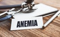 ANEMIA word written on card on wooden table with medical background