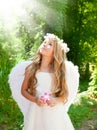 Angel children girl in forest with flower in hand