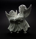 Guardian angel on a dark background two angels are reading a book Royalty Free Stock Photo