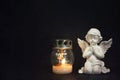 Angel and votive candle on black grunge background with copy space