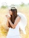 Angel girl in golden field with white wings Royalty Free Stock Photo